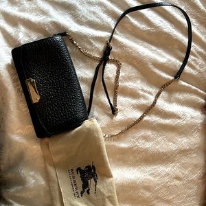 Black leather Burberry clutch with shoulder strap and gold hardware.